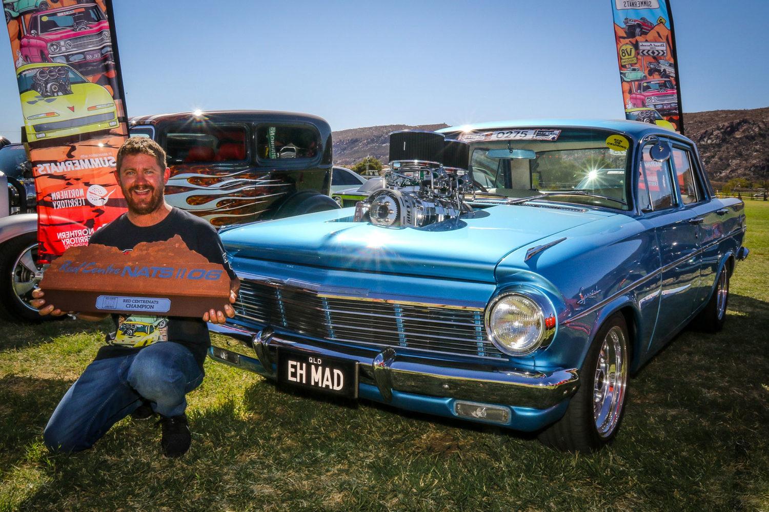 man with trophy infront of car